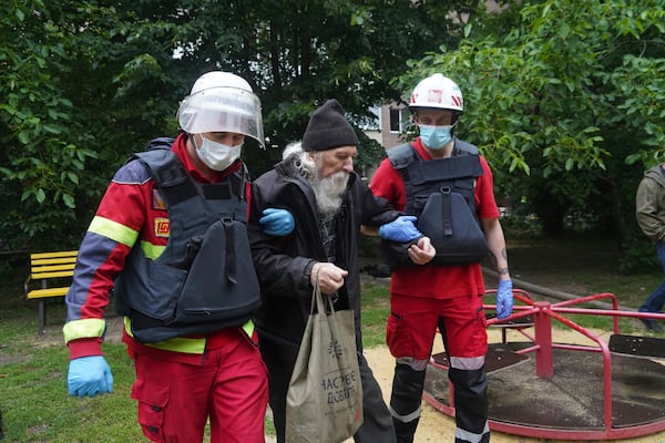 An elderly man is assisted after a Russian attack that hit a residential building in Kharkiv, Ukraine, Saturday, June 7, 2025. (AP Photo/Andrii Marienko)