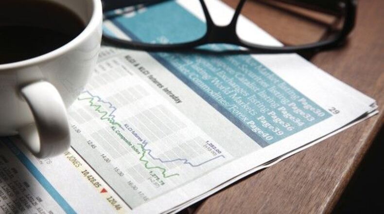 Cup of coffee and set of glasses sitting on top of a stock market graph in a newspaper.