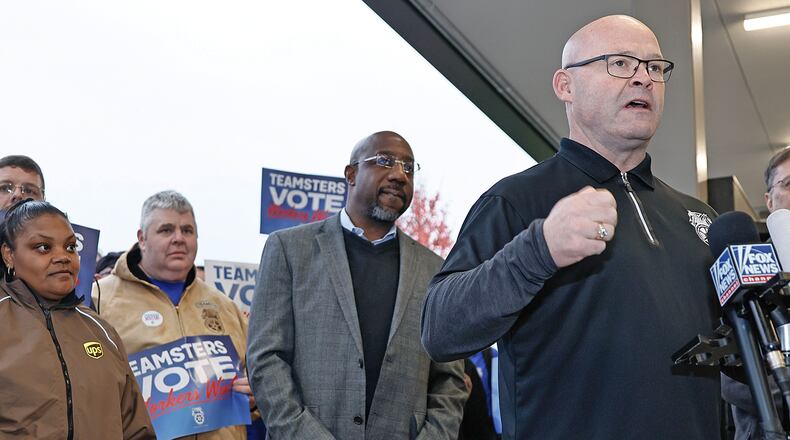 Teamsters general president Sean O’Brien speaks to the media as Sen. Raphael Warnock looks on during a campaign rally at the UPS Smart Hub facility in Atlanta on Monday, Dec. 5, 2022. (Natrice Miller/Atlanta Journal-Constitution/TNS)