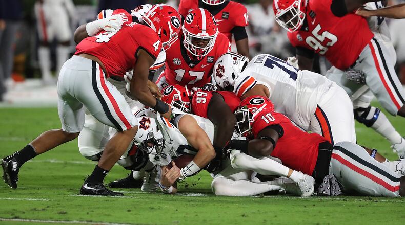 Georgia defenders pile on Auburn quarterback Bo Nix for no gain during the first quarter of Saturday's game in Athens. Georgia kept Auburn out of the end zone and only allowed a pair of field goals in the 27-6 victory. (Curtis Compton/AJC)