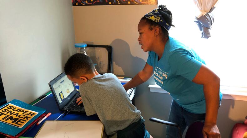 Tiffany Shelton helps her 7-year-old son, P.J. Shelton, a second-grader, during an online class at their home in Norristown, Pa., on Thursday, Sept. 3, 2020. Norristown Area School District plans to offer online-only instruction through at least January 2021. (AP Photo/Michael Rubinkam)