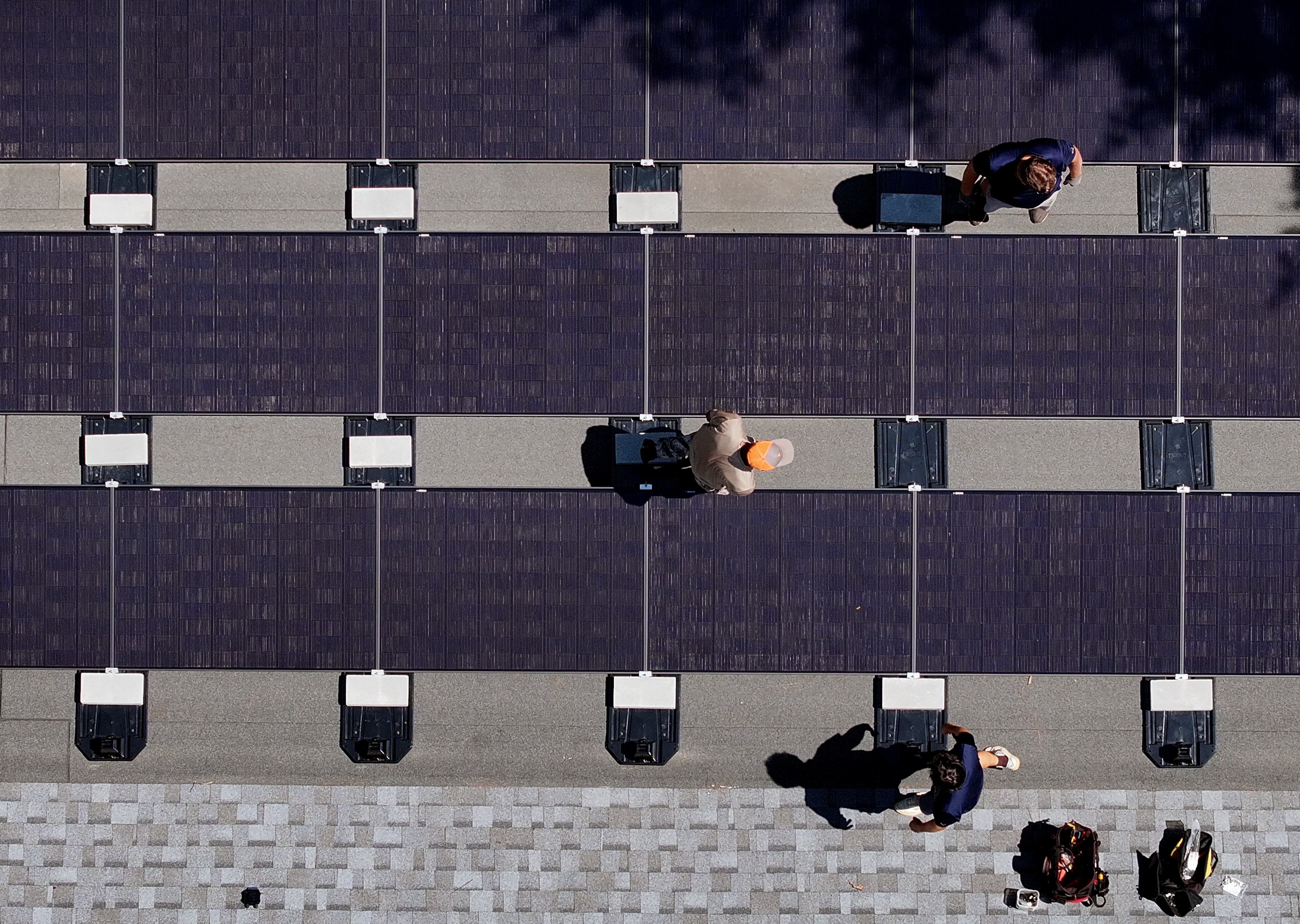 Workers with Custom Solar Solutions install solar panels on the roof of the Adler family home, Thursday, July 17, 2025, in North Druid Hills. Companies like Custom Solar Solutions, who have already been impacted by tariff-driven cost increases, expect to be hit even harder by the reconciliation bill which eliminates a crucial tax incentive.(Hyosub Shin / AJC)