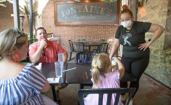 Alex Hall (right) takes a lunch order from Lenoir Woolverton as she joined her parents, Charles and Pate, on the back porch of Fontaine's Oyster House in Atlanta in 2020. (Steve Schaefer/AJC 2020)
