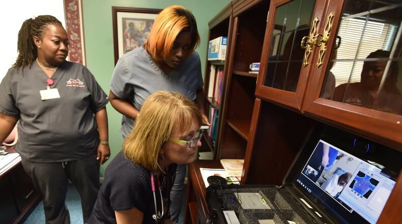 At the Community Health Care Systems center on Hamilton Street in Sparta, Ga., nurse practitioner Kemberly Smith (foreground) and medical assistants Keisha Hill and Joy Robinson examine a patient via telemedicine on Aug. 27, 2015. BRANT SANDERLIN /BSANDERLIN@AJC.COM