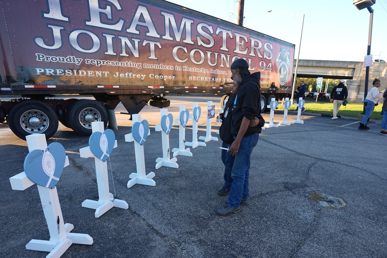 Allen Wilson, right, stands with an attendee after they wrote on crosses for victims during a vigil Thursday, Nov. 6, 2025, in Louisville, Ky., after a UPS plane crashed at Louisville Muhammad Ali International Airport. (Darron Cummings/AP)