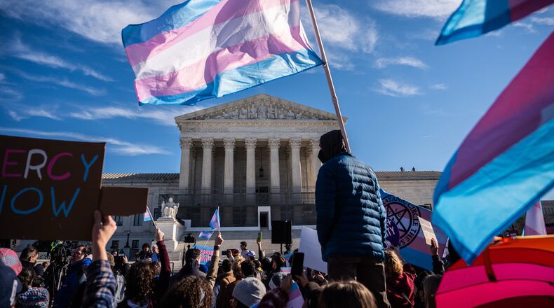 Protesters wave transgender pride flags outside the Supreme Court as it hears arguments over state laws barring transgender girls and women from playing on school athletic teams, Tuesday, Jan. 13, 2026, in Washington. (AP Photo/Julia Demaree Nikhinson)