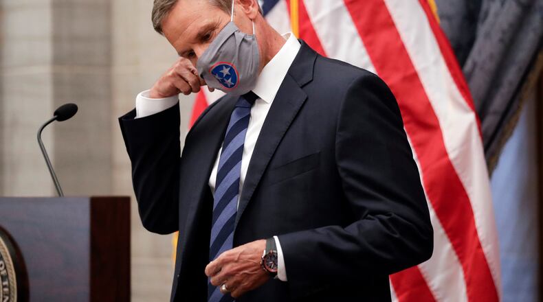 FILE - In this July 1, 2020, file photo, Tennessee Gov. Bill Lee removes his mask as he begins a news conference in Nashville, Tenn. Tennessee was one of the first states to begin reopening in late April after Lee reluctantly issued a safer-at-home order that forced businesses to close. Since then, case numbers have continued to rise in part due to more testing, but also because of an increase in community spread of the disease. (AP Photo/Mark Humphrey, File)