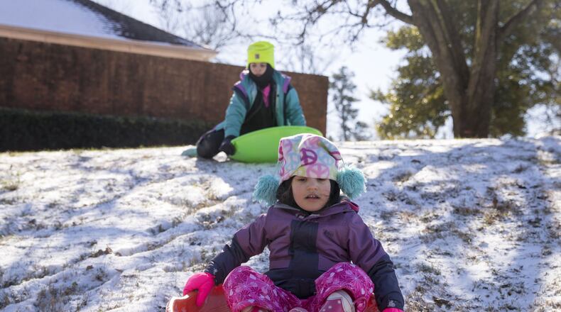 01/18/2018 — Dunwoody, GA - Marcy Ringel,4, foreground, slides down a snow covered hill as her older sister, Lucy Ringel, 8, prepares to follow in Dunwoody, Thursday, January 18, 2018. A wintery mix on Wednesday left roads around metro Atlanta covered in snow and ice. Schools around metro Atlanta were shut down due to the weather, both Wednesday and Thursday. The weather forced Governor Nathan Deal to proclaim a state of emergency for more than 80 counties. Temperatures are forecasted to reach above freezing Thursday afternoon which can help melt the black ice that is still prevalent on the roads throughout metro Atlanta. ALYSSA POINTER/ALYSSA.POINTER@AJC.COM
