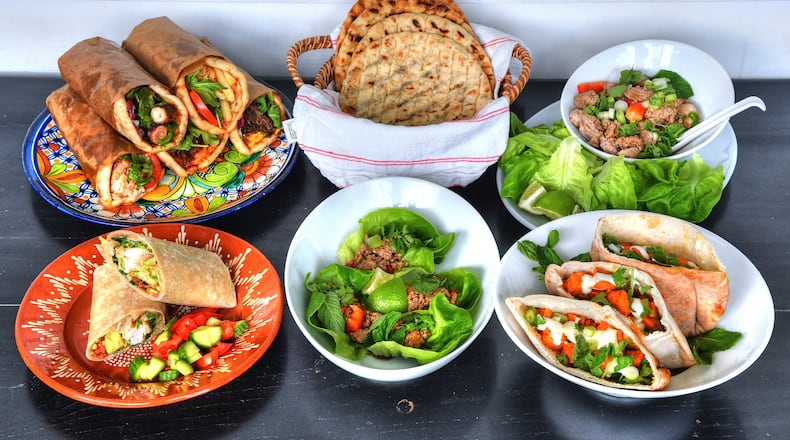 Hand-held meals that will tempt you include (top row, from left) assorted pita wraps from Kyma executive chef Pano Karatassos' Lamb Shack, Homemade Pita Bread (a recipe from Karatassos' cookbook), a DIY setup for Laotian Larb Lettuce Wraps; and (bottom row, from left) Poco Loco chef's Grilled Chicken BLT Burrito With BBQ Crema, Laotian Larb Lettuce Wraps and Yalla executive chef Todd Ginsberg's Roasted Sweet Potato Pockets With Whipped Feta Dressing. Styling by Lisa Hanson / Chris Hunt for the AJC