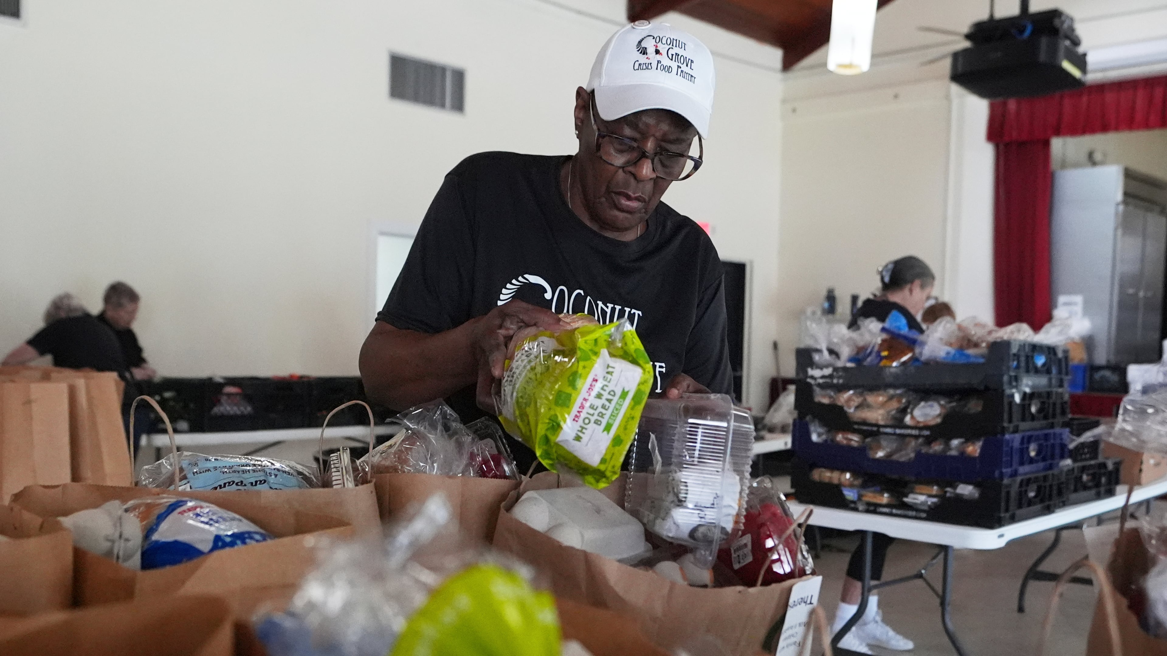 FILE - Volunteer Ollie Taylor fills bags with food at the Coconut Grove Crisis Food Pantry, which offers fresh food and meals free of charge on a weekly basis to residents, Aug. 26, 2025, in the Coconut Grove neighborhood of Miami. (AP Photo/Lynne Sladky, File)