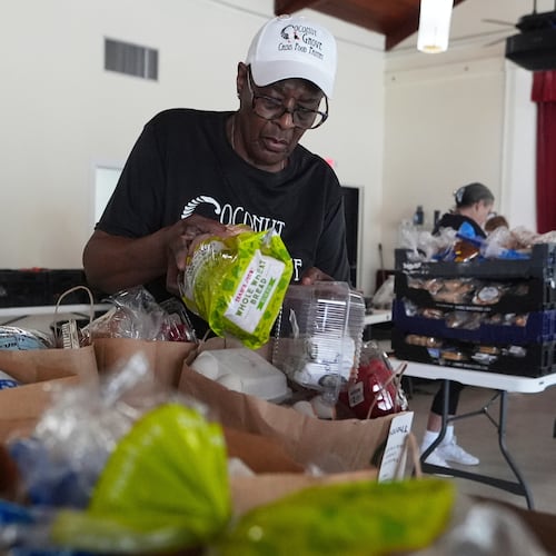 FILE - Volunteer Ollie Taylor fills bags with food at the Coconut Grove Crisis Food Pantry, which offers fresh food and meals free of charge on a weekly basis to residents, Aug. 26, 2025, in the Coconut Grove neighborhood of Miami. (AP Photo/Lynne Sladky, File)