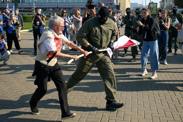 FILE - A police officer tries to take away an old Belarusian national flag from Nina Bahinskaya's, 73, hands during an opposition rally to protest the official presidential election results in Minsk, Belarus, Saturday, Sept. 26, 2020. (AP Photo/TUT.by, File)