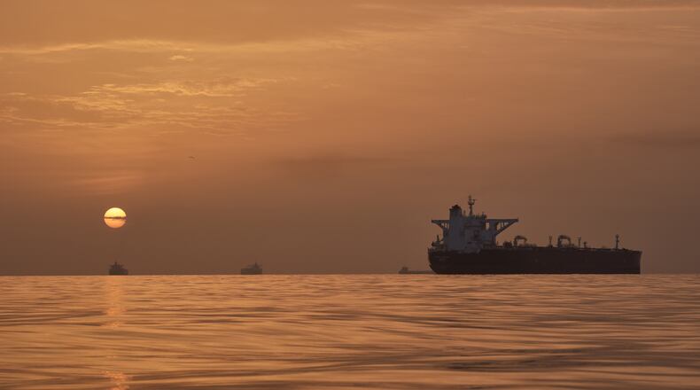 The sun rises behind tankers anchored in the Strait of Hormuz off the coast of Qeshm Island, Iran, Saturday, April 18, 2026. (AP Photo/Asghar Besharati)