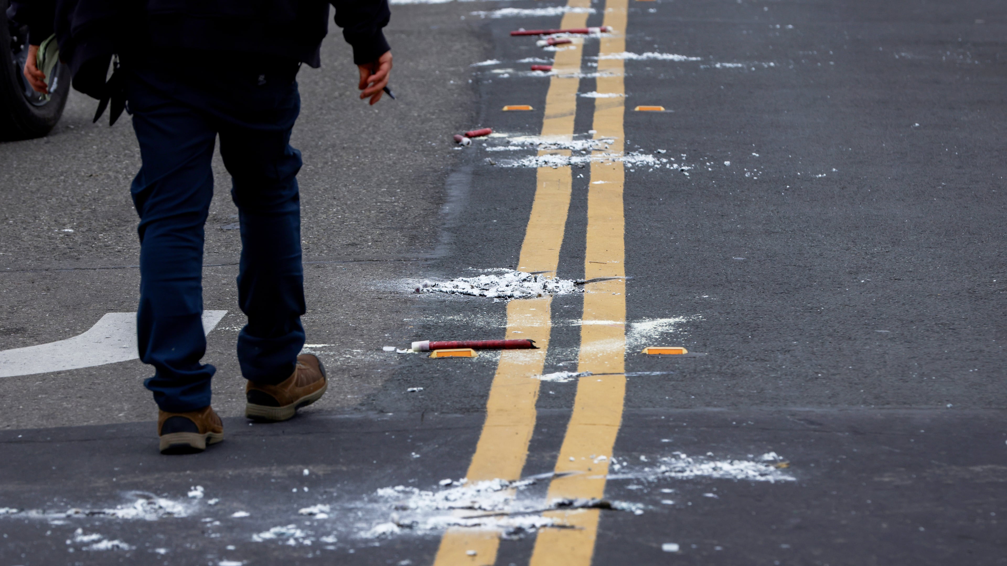 A man walks near the remains of flares as investigators with the San Joaquin Sheriff's Department work near the site of Saturday's shooting at a banquet hall in Stockton, Calif., Sunday, Nov. 30, 2025. (Brontë Wittpenn/San Francisco Chronicle via AP)