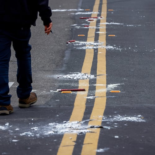 A man walks near the remains of flares as investigators with the San Joaquin Sheriff's Department work near the site of Saturday's shooting at a banquet hall in Stockton, Calif., Sunday, Nov. 30, 2025. (Brontë Wittpenn/San Francisco Chronicle via AP)