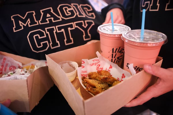 An Atlanta Hawks fan holds an order of lemon pepper wings as they wear Magic City sweatshirts before the NBA game against the Orlando Magic at State Farm Arena on Monday, March 16, 2026, in Atlanta. (Jason Getz/AJC)