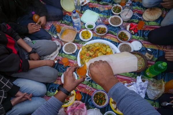 A man serves a juice as Palestinians prepare for Iftar, the fast-breaking meal during Ramadan in a street of the war-devastated Beit Lahia, northern Gaza Strip, Saturday, March 15, 2025. (AP Photo/Jehad Alshrafi)