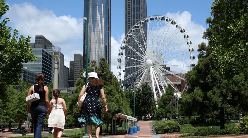 A family walks through Centennial Olympic Park with the SkyView Ferris wheel in the background in downtown Atlanta.