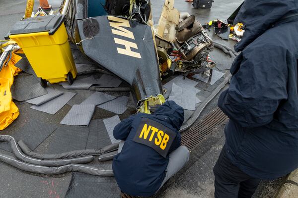 In this image released by the National Transportation Safety Board, an NTSB team surveys the wreckage, April 11, 2025, in Jersey City, N.J., recovered from the Bell 206 L-4 helicopter that crashed into Hudson River on April 10, between New York City and New Jersey. (NTSB via AP)