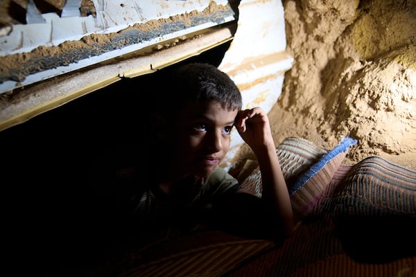 Mohammed Abu Ganima, 7, peers out of a makeshift shelter in his Bedouin village: a minibus buried in the earth to try to protect his family from incoming Iranian fire, in the Negev Desert in southern Israel, early Wednesday, June 18, 2025. (AP Photo/Maya Alleruzzo)