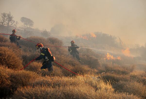 Firefighter uses a hose as the try to extinguish the blaze near the town of Ierapetra on the south coast of Crete island, Greece, Thursday July 3, 2025, as a fast-moving wildfire prompted authorities to clear villages and coastal areas, officials said. (InTime News via AP)