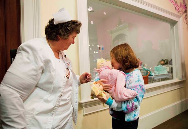 FILE - Talon Shaffer, right, kisses a Cabbage Patch Kid after it was delivered by Cyndi Pappadouplos, a "licensed patch nurse" at Babyland General Hospital, the birthplace of Cabbage Patch Kids, in Cleveland, Ga., on Nov. 21, 2014. (AP Photo/David Goldman, File)