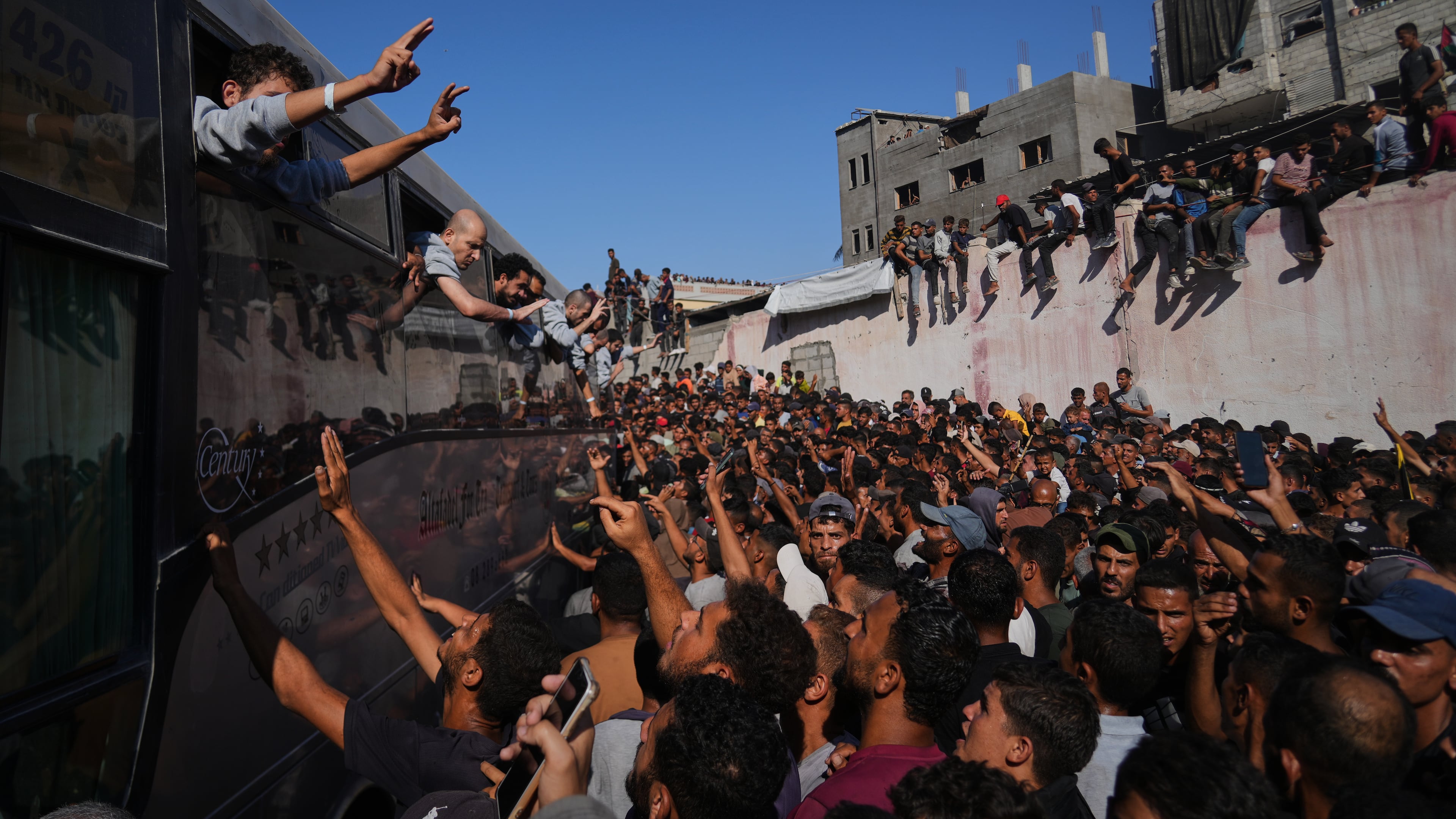 People gather to greet freed Palestinian prisoners arriving on buses in the Gaza Strip after their release from Israeli jails under a ceasefire agreement between Hamas and Israel, outside Nasser Hospital in Khan Younis, southern Gaza Strip, Monday, Oct. 13, 2025. (AP Photo/Abdel Kareem Hana)