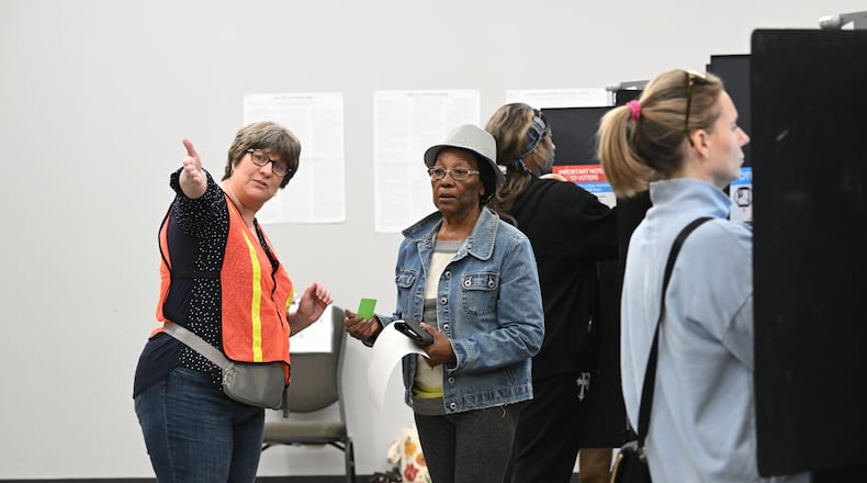 Joyce Fraser of Marietta, is directed by a poll worker after filling her ballot at the polling station Tuesday during advance voting at the Cobb County Elections and Registration Main Office in Marietta. (Hyosub Shin / AJC)