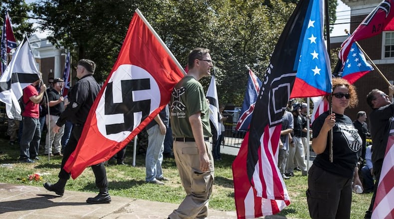 A white nationalist carries a Nazi flag during a protest in Charlottesville, Va., Aug. 12, 2017. (AJC File)