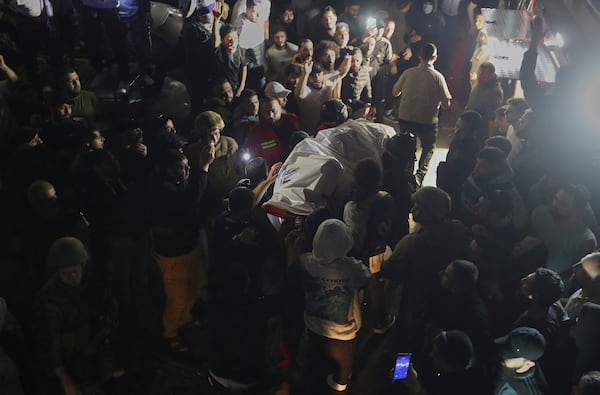 Rescue workers carry a dead body of a person who was killed by an apparent Israeli airstrike that hit an apartment building, in the southern port city of Sidon, Lebanon, early Friday, April 4, 2025. (AP Photo/Mohammed Zaatari)