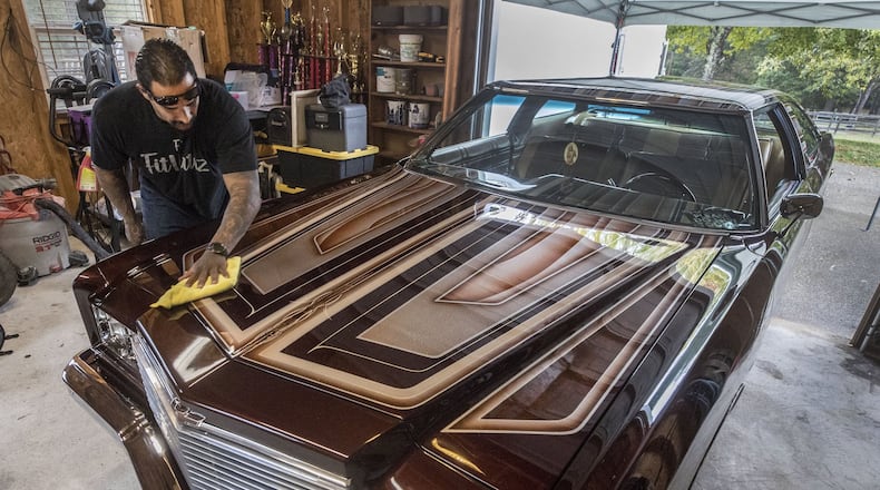 Alfredo “Freddy” Quintero gives his Impala a wipe down as he waits for the Hot Wheels trailer to pick up his car for the event. Quintero and his custom 1975 Chevy Impala are headed to the Hot Wheels Tour Grand Finale in Vegas, where the winner will be inducted into the Hot Wheels Garage of Legends. Bob Andres/robert.andres@ajc.com