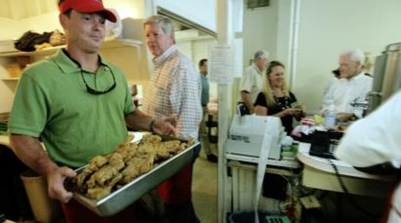 Michael Greene (left) delivers fried pork chops to the cafeteria line at Matthews Cafeteria. His father, owner Charles Greene, is behind him.