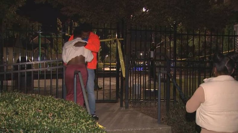 Mourners hug each other at the scene of a deadly shooting Monday night at an apartment complex on Fulton Street.