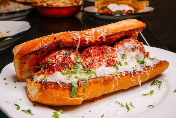 A large, messy meatball sub sprinkled with Parmesan shreds.