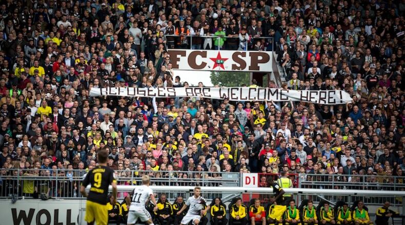 Fans of FC St. Pauli, a second-division German soccer team, hold up a banner welcoming refugees to an exhibition match at their home ground in Hamburg, Sept. 8, 2015. Famous for its punk-rock ethos and social conscience, St. Pauli offered refugees 1,000 free tickets to a match that also raised money to finance search-and-rescue operations in the Mediterranean. (Gordon Welters/The New York Times)