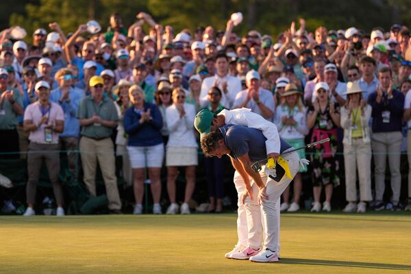 Rory McIlroy, of Northern Ireland, is hugged by caddie Harry Diamond after winning in a playoff against Justin Rose, of England, after the final round the Masters golf tournament, Sunday, April 13, 2025, in Augusta, Ga.(AP Photo/Ashley Landis)