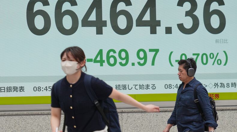 People walk in front of an electronic stock board showing Japan's Nikkei index at a securities firm Tuesday, June 2, 2026, in Tokyo. (AP Photo/Eugene Hoshiko)