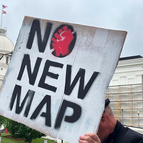 A demonstrator holds up a sign outside the Alabama Statehouse in Montgomery, Ala., on Thursday, May, 7 2026. (AP Photo/Kim Chandler)