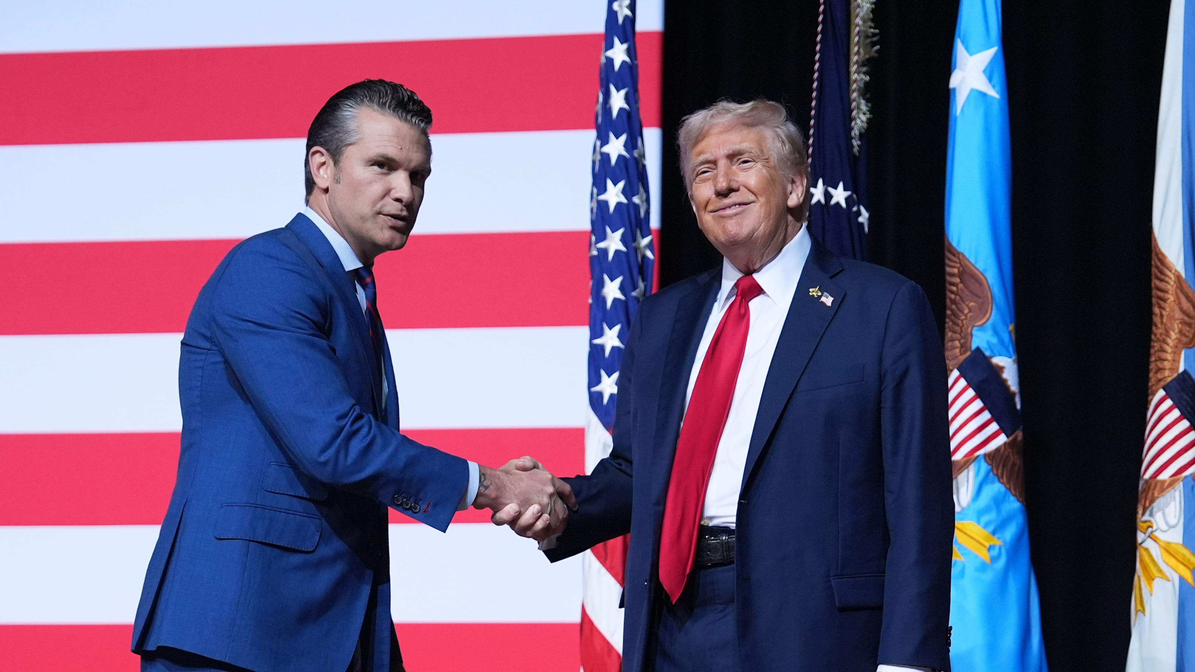 President Donald Trump is greeted by Secretary of Defense Pete Hegseth before speaking to a gathering of top U.S. military commanders at Marine Corps Base Quantico, Tuesday, Sept. 30, 2025, in Quantico, Va. (AP Photo/Evan Vucci)