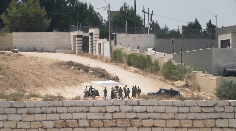 Israeli settlers patrol a road in front of besieged Palestinian houses, in the occupied West Bank village of Qusra, south of Nablus, Monday, Aug. 17, 2026. (AP Photo/Majdi Mohammed)