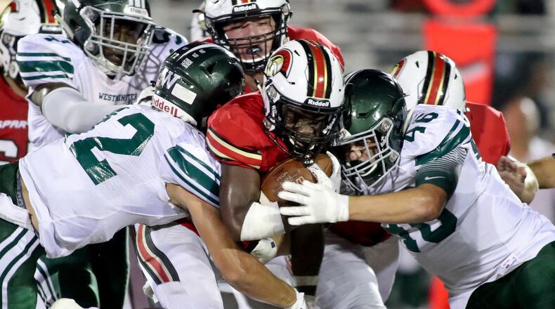 GAC running back Tyler Bride (4) is tackled by Westminster defensive back Chance Loeffler (12) and a teammate in the second half at Greater Atlanta Christian Friday, August 24, 2018, in Norcross, Ga. PHOTO / JASON GETZ