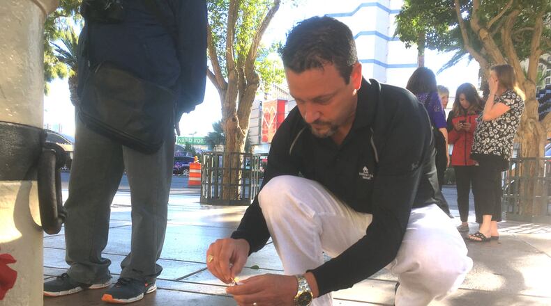 Steve Titzer lights a candle in memory of the Las Vegas shooting victims. He and his wife were about 15 feet from the stage when the rampage began, and escaped by running against the crowd. Photo: Jennifer Brett, jbrett@ajc.com