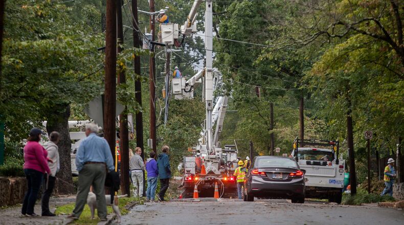 Residents walk on Adair Street as workers from Utility Lines Construction Services, a Delaware based company, work to restore power, Tuesday, Sept. 12, 2017, in Decatur, Ga. BRANDEN CAMP/SPECIAL
