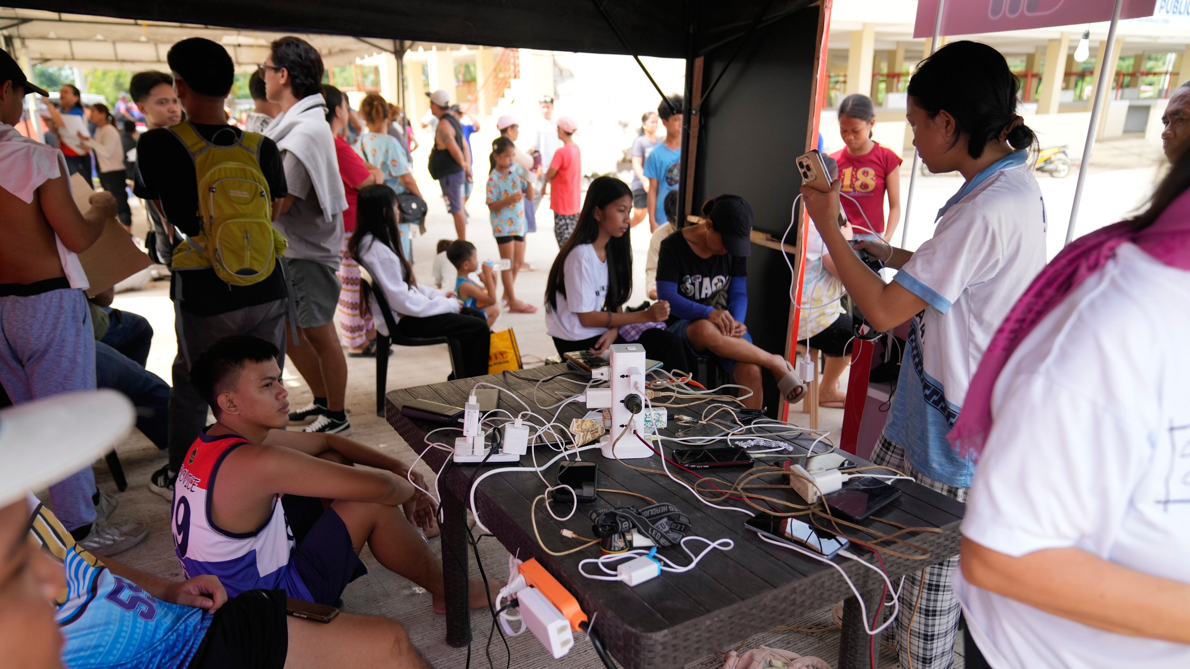 Survivors of Tuesday's earthquake charge their phones on Thursday, Oct. 2, 2025 in San Remigio, Cebu Province, Central Philippines. (AP Photo/Aaron Favila)