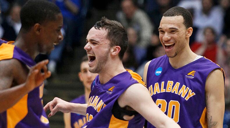 Albany guard Peter Hooley (center) celebrates with guard D.J. Evans (left) and forward Gary Johnson after Albany defeated Mount St. Mary's 71-64 in a first-round game of the NCAA college basketball tournament Tuesday, March 18, 2014, in Dayton, Ohio.
