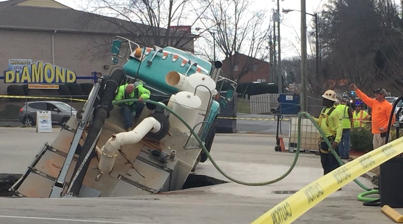 A worker climbs on a truck that is stuck in a sinkhole in Hall County. (Credit: Channel 2 Action News)