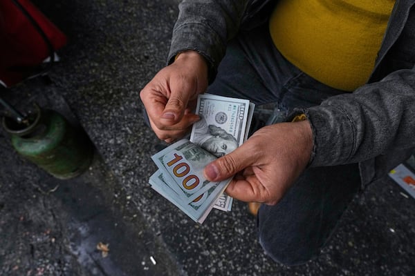 A street money exchanger poses for a photo without showing his face as he counts U.S. dollars at Ferdowsi square, Tehran's go-to venue for foreign currency exchange, in downtown Tehran, Iran, Saturday, April 5, 2025. (AP Photo/Vahid Salemi)
