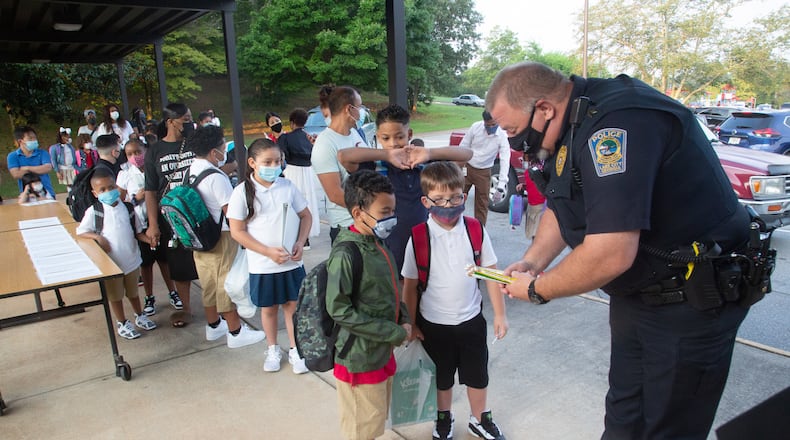 Lake City Georgia police officer J. Yancey hands out pencils on the first day of school at Lake City Elementary Monday, August 2, 2021.STEVE SCHAEFER FOR THE ATLANTA JOURNAL-CONSTITUTION