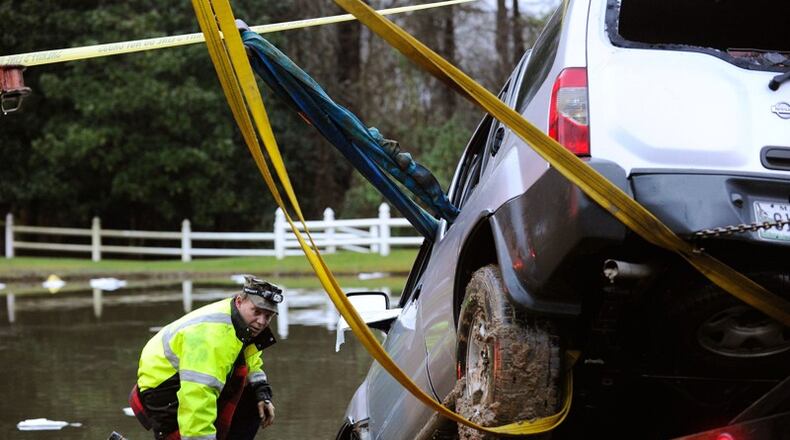 Officials remove an SUV that was submerged in a pond off Batesville Road in rural Cherokee County after its driver was rescued by firefighters near Atlanta National Golf Course early Monday morning, Dec. 29, 2014. The woman, who later died in a hospital, had called 911 on her cell phone, but rescuers were unable to find her in time. AJC FILE