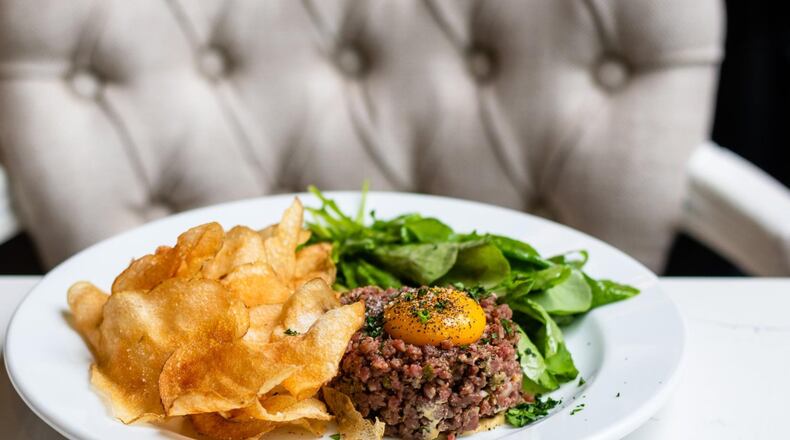 Steak tartare at the Brasserie is served with classic accouterments: dijon, shallots, cornichons, capers and an egg yolk. It’s served with house-made potato chips and a pile of bright salad greens. CONTRIBUTED BY HENRI HOLLIS